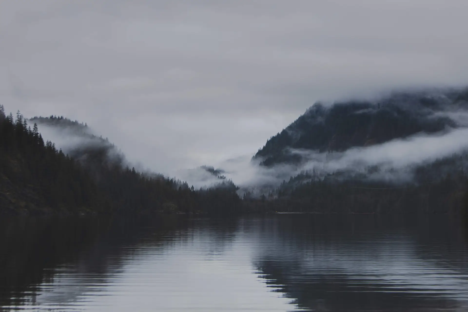 Serene mountain lake waters shrouded in morning fog