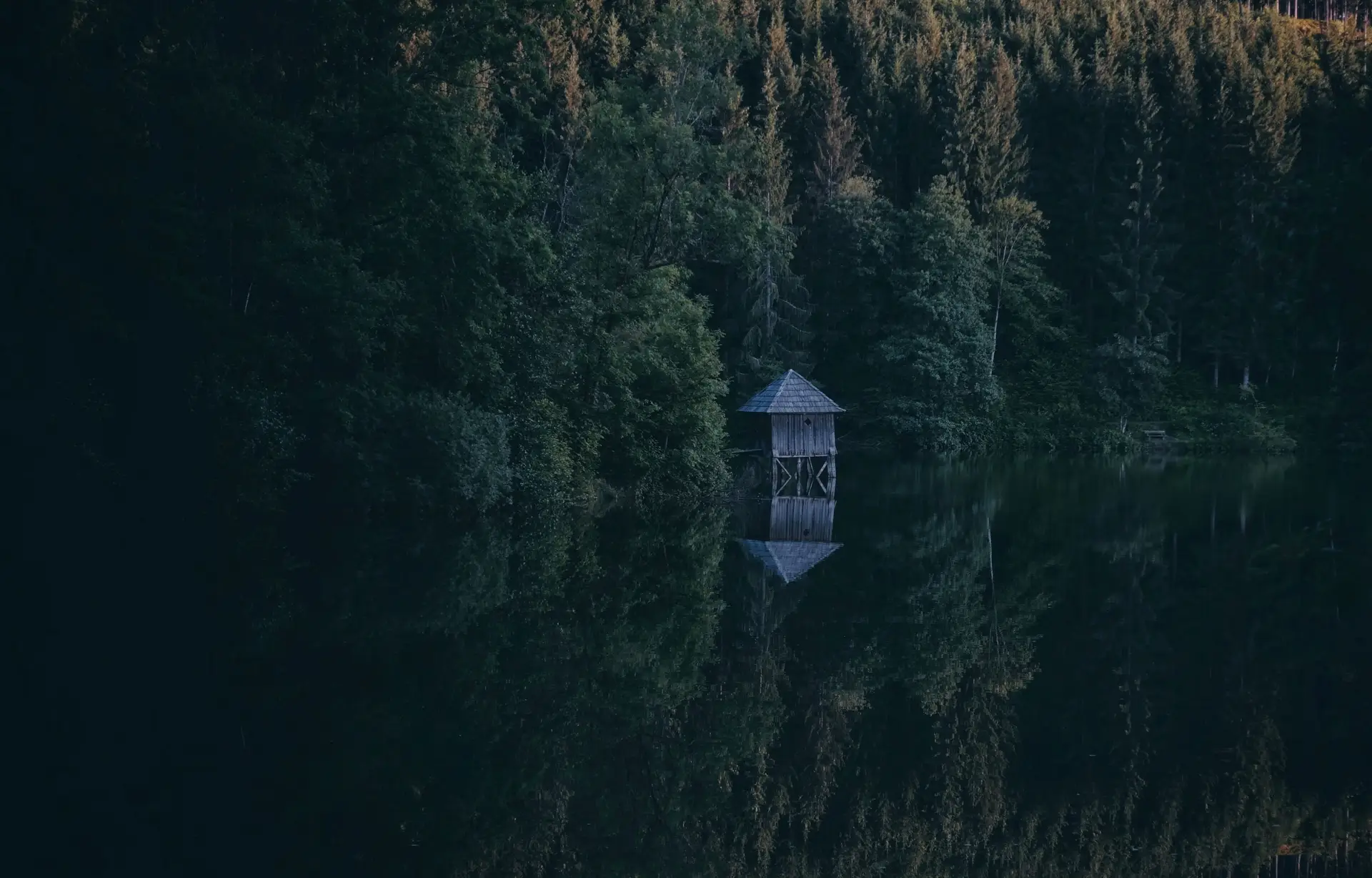Quiet wooden cottage reflecting gently in deep water