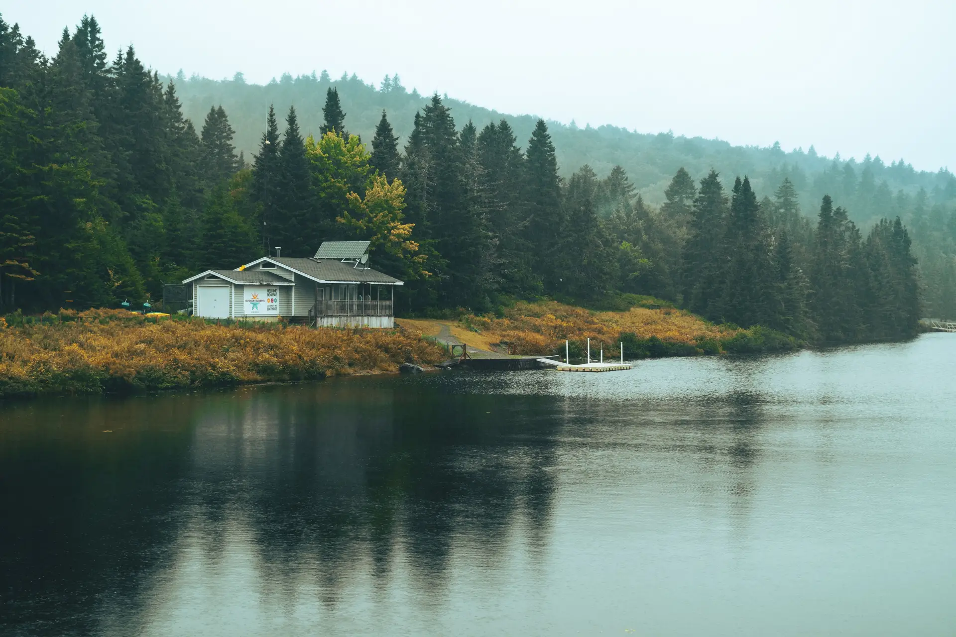 Misty autumn foliage reflecting in a calm Canadian lake