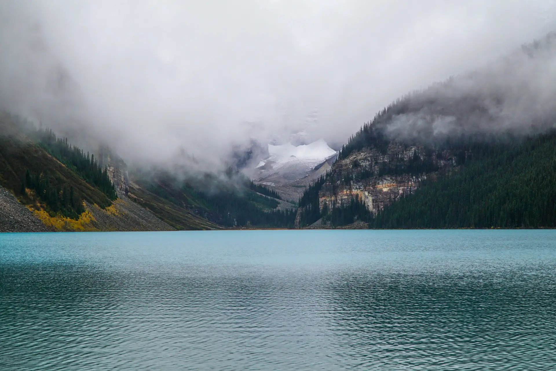 Scenic view of foggy Lake Louise surrounded by mountains in Banff, Canada